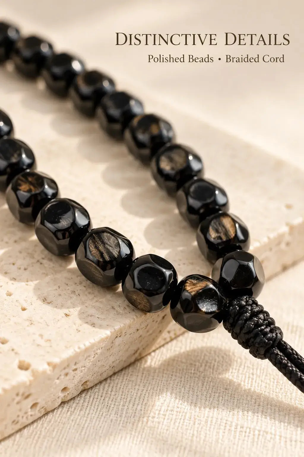 Close-up of polished black coconut beads with warm golden-brown highlights and a black cord knot